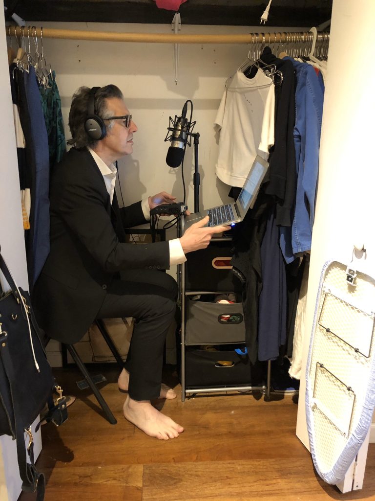 a man recording into a microphone in a wardrobe