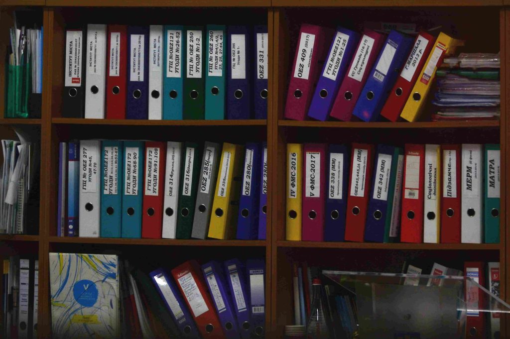 a bookshelf full of coloured lever arch files and folders