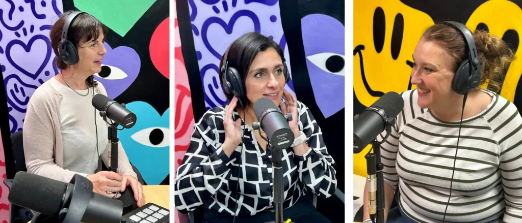 3 women sit in front of microphones and they are wearing black headphones