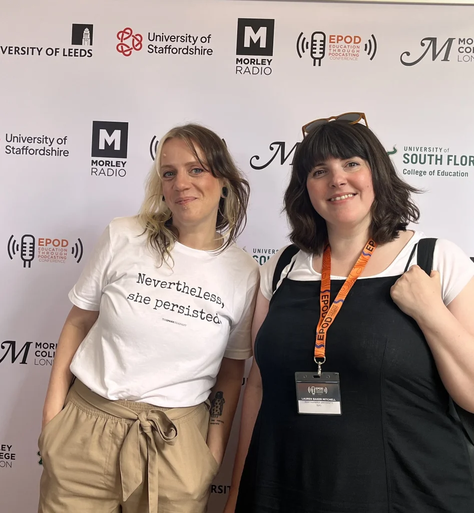 two women stand in front of a board with logos on it