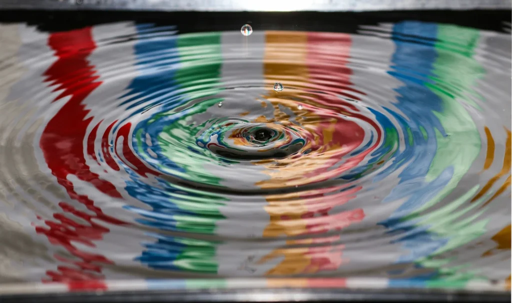 Colourful ripples spreading across the surface of water.