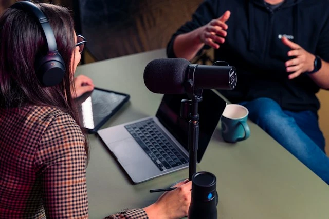 People sitting around a table recording a podcast.